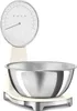 A cream-colored Smeg kitchen scale with a silver bowl on a white background. Voir les images du produit