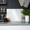 A kitchen counter with a marble cutting board, olive oil, salt and pepper grinders, and a potted plant. Náhľad obrázku produktu