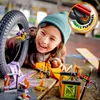 A young girl is playing with LEGO City Stunt-Park set, which includes a motorcycle, spider cage, and minifigure. Náhled obrázku produktu