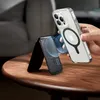 A hand holding a clear phone case with a magnetic ring, about to attach it to a black magnetic wallet stand on a wooden table. Anteprima dell’immagine prodotto