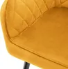 A close-up view of a mustard yellow upholstered chair, showing the quilted texture of the fabric and a portion of a black metal leg. Produktbild-Vorschau
