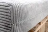 Close-up of a gray corduroy cushion with a zipper, resting on a wooden pallet. Produktbild-Vorschau