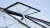 Close-up view of an open automatic greenhouse vent mechanism against a blue sky. Produktbild-Vorschau