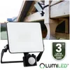 A LUMILED LED floodlight with a motion sensor is shown in the foreground, with a close-up of a similar light fixture mounted on wooden beams in the background. A warranty badge is also visible. Náhled obrázku produktu
