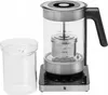 A WMF electric kettle and a clear glass container are shown against a white background. The kettle has a glass body, a stainless steel infuser basket, and a black handle. It sits on a black base with illuminated control buttons. The separate glass containe Náhled obrázku produktu