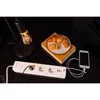 A desk setup with a power strip, a lamp, a croissant on a plate, and a smartphone charging. Produktbild-Vorschau