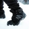 A person wearing black pants and black winter boots walking in the snow. Produktbild-Vorschau