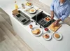A person is preparing fruit and pancakes in a modern kitchen sink area. Voir les images du produit