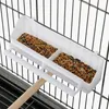 A close-up view of a white plastic bird feeder attached to a bird cage, filled with birdseed. Produktbild-Vorschau