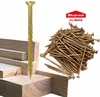 A pile of gold-colored screws next to a few wooden planks, with a single screw prominently displayed in the foreground. Produktbild-Vorschau