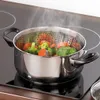 A steaming vegetable steamer insert is placed in a pot on a stovetop. Produktbild-Vorschau