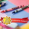 Two Crayola crayons are shown on a background of pink and blue paper. A red ribbon banner with text and a sun-shaped graphic are overlaid on the image. Produktbild-Vorschau