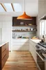 A modern kitchen with white cabinets, wooden floors, and a large orange pendant light. Produktbild-Vorschau