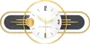 A modern wall clock with a gold frame and a white face, featuring gold hands and black hour markers. The clock has a decorative dark gray element with gold horizontal lines. Produktbild-Vorschau