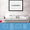 A living room scene with a sofa and a framed picture on the wall, with product size information displayed below. Produktbild-Vorschau