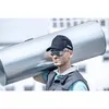A man carrying a large metal pipe on his shoulder, wearing a cap and safety glasses. Anteprima dell’immagine prodotto