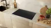 A modern kitchen countertop with an induction hob, sink, and decorative items. Náhľad obrázku produktu