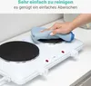 A hand is wiping a portable double burner electric stove with a blue cloth. Náhled obrázku produktu
