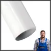 A man in a blue work uniform stands next to a white pipe. Anteprima dell’immagine prodotto
