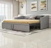 A gray sofa bed with a yellow mattress is shown in a room with sheer curtains and artwork on the wall. Produktbild-Vorschau