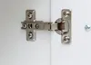A close-up view of a cabinet hinge attached to a white surface. Produktbild-Vorschau