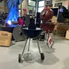 A retail store setting with various products on display, including grills and decorative items. Produktbild-Vorschau