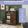 A rustic-style storage cabinet with a sliding barn door, displayed in a home setting with decorative items and packaging. Náhľad obrázku produktu