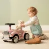 A baby is playing with a pink ride-on car and a teddy bear. Produktbild-Vorschau