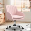 A pink velvet office chair with a chrome base and wheels is shown in a room with a wooden dresser and blinds in the background. Produktbild-Vorschau