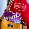 A close-up of a handbag with a packet of Vivil candies inside, and a red garment with text overlay. Produktbild-Vorschau