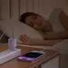 A woman sleeps in bed while a phone and charger are on a nightstand. Anteprima dell’immagine prodotto