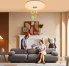 A couple is sitting on a sofa in a living room, looking at a document. A ceiling light with musical notes is visible above them. Voir les images du produit