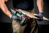 A person is holding a cordless jigsaw and a piece of wood. Voir les images du produit