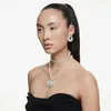 A woman wearing multiple necklaces and earrings, posing against a white background. Produktbild-Vorschau