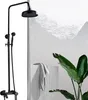 A black shower fixture with a rain showerhead and a handheld showerhead is shown in a modern bathroom setting with a large plant and a folded towel on a concrete block. Produktbild-Vorschau