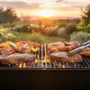 A barbecue grill with various meats and vegetables cooking on it during sunset. Produktbild-Vorschau