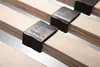 A close-up view of wooden slats of a bed frame with black plastic holders. Produktbild-Vorschau