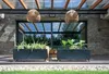 Two rectangular planters with plants are placed on a wooden deck in front of a modern house with large glass doors. Produktbild-Vorschau