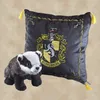 A plush badger toy and a Hufflepuff crest pillow are displayed against a textured background. Produktbild-Vorschau