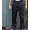 A person wearing black pants standing in front of a weathered blue door and a brick wall. Produktbild-Vorschau