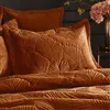 A close-up view of a rust-colored velvet duvet cover and pillow with a raised leaf pattern. Anteprima dell’immagine prodotto