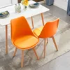 Two orange dining chairs are placed next to a white dining table. Voir les images du produit