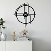 A modern black metal wall clock with a minimalist design is displayed on a white wall above a white cabinet. Produktbild-Vorschau