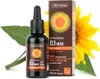 A bottle of vitamin D3 drops next to its packaging, with a sunflower and leaves in the background. Produktbild-Vorschau