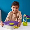 A young boy is sitting at a table with a lunchbox and a water bottle. Náhľad obrázku produktu
