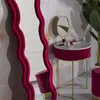A vanity table with a mirror and makeup is set up in a room with decorative wavy mirrors and a plant. Podgląd zdjęcia produktu