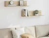 Two wooden shelves mounted on a white wall above a sofa, decorated with books, a clock, a framed picture, and a potted plant. Produktbild-Vorschau