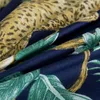 A close-up view of a fabric with a jungle-themed print, featuring a leopard pattern and green leaves. Náhled obrázku produktu