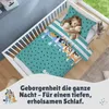 A young girl sleeps in a crib with Bluey-themed bedding. Produktbild-Vorschau