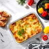 A top-down view of a lasagna dish with grilled chicken, bell peppers, and herbs arranged around it on a marble surface. Náhľad obrázku produktu